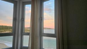 a room with three windows looking out at the ocean at C&C Suite in San Ciprián +5 photos