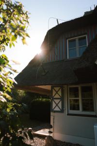 a house with the sun shining on the roof of it at Sünn un See - Hortensienblick in Ahrenshoop