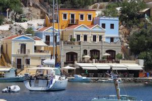 a boat in the water in front of buildings at Odyssia in Symi