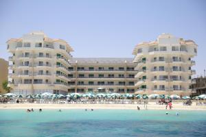 a view of a hotel from the beach with people in the water at Beau Site Hotel in Marsa Matruh