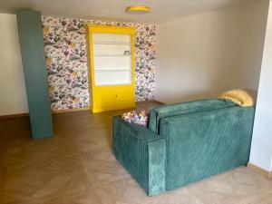 a living room with a green couch and a yellow door at Loft dans les vignes in La Cadière-dʼAzur