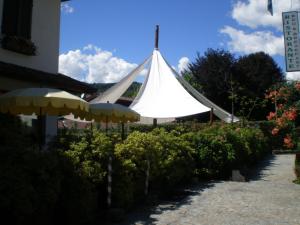 uma tenda branca num jardim ao lado de um edifício em Locanda Verbena em Stresa