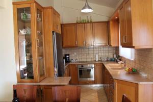 a kitchen with wooden cabinets and stainless steel appliances at Helen's Sounio Apartments in Sounio