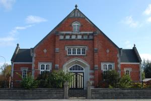 a large red brick building with a black gate at Hall on the Terrace in Temuka