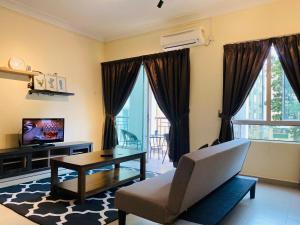 a living room with a couch and a tv at Desaru Beach Luxury Suite Pool View C1 in Bandar Penawar