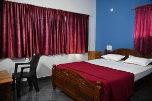 a bedroom with a bed with red curtains and a chair at Ramleela Stay, Gokarna in Ankola