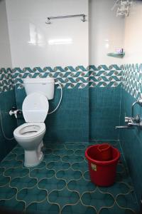 a bathroom with a toilet and a red bucket at Ramleela Stay, Gokarna in Ankola