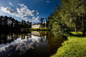 a house is reflected in the water of a lake at Hotel Chateau Orlice in Letohrad