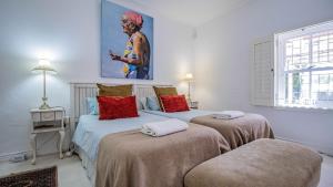 a bedroom with two beds and a painting on the wall at Griki in Paternoster