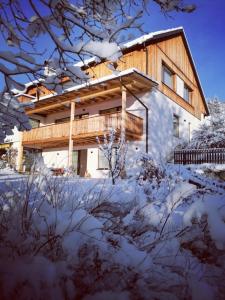 a house with a wooden deck in the snow at Appartement Rehlein in Mauterndorf
