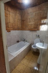 a bathroom with a tub and a toilet and a sink at Ndou The Rocks Lodge in Hammanskraal Station +31 photos