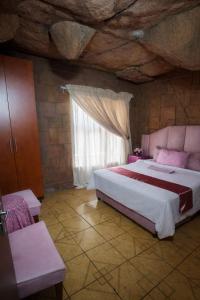 a bedroom with a large bed and a window at Ndou The Rocks Lodge in Hammanskraal Station
