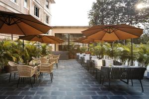 eine Terrasse mit Tischen, Stühlen und Sonnenschirmen in der Unterkunft Hotel Anuttara, Boudha in Baudhatinchule