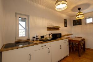 a kitchen with white cabinets and a sink and a table at Menasagi Sit&Dream Cottage in Menasag-Ujfalu