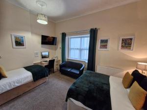 a hotel room with two beds and a chair at Hen Dy in Llandudno