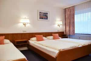 zwei Betten in einem Schlafzimmer mit zwei Lampen und einem Fenster in der Unterkunft Hotel Am Steinberg in Hildesheim
