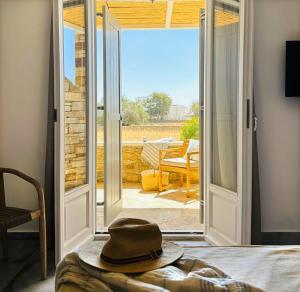 a hat sitting on a bed in front of a sliding glass door at Olive Tree Homes in Ios Chora
