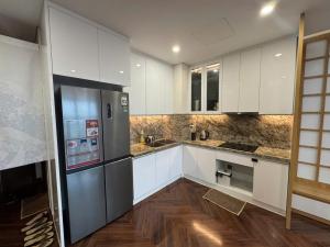 a kitchen with white cabinets and a stainless steel refrigerator at QNC Taiyo Homestay in Hai Phong