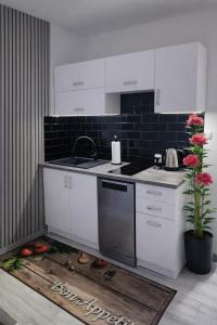 a kitchen with white cabinets and a sink and flowers at Pokoje Koral in Mikołajki
