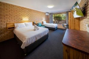 a hotel room with a bed and a desk and a bed and a couch at Cambridge Motel in Mitchell