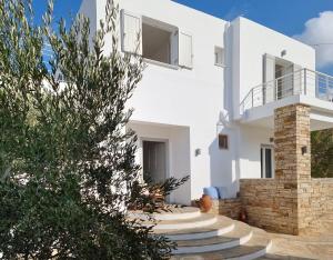 a white villa with a staircase leading up to it at Olive Tree Homes in Ios Chora