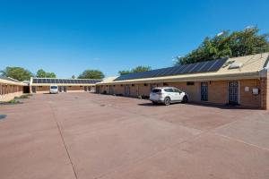 a building with a car parked in a parking lot at Cambridge Motel in Mitchell