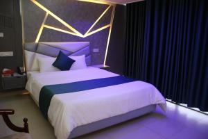a bedroom with a king sized bed with purple curtains at City Inn Ltd in Khulna