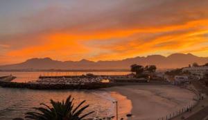 a sunset over a beach and the ocean at Beachside Bliss Gordons Bay in Gordonʼs Bay