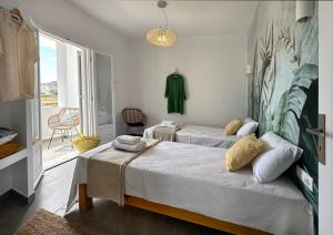 a bedroom with two beds and a large window at Olive Tree Homes in Ios Chora
