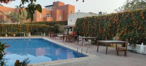 a swimming pool with tables and chairs next to a hedge at Hotel Sugan Niwas Palace in Jaipur