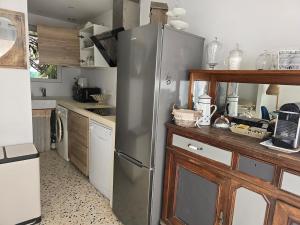 a kitchen with a stainless steel refrigerator and wooden cabinets at La brise marine - proche de la mer in Valras-Plage +6 photos