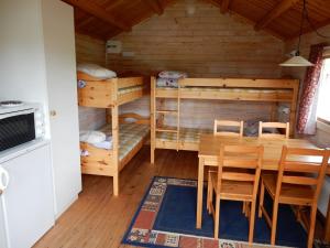 a room with a table and chairs and bunk beds at Burträsk Camping & Stugby in Burträsk