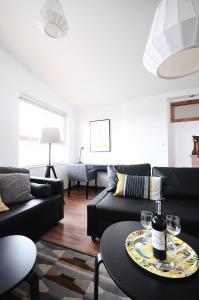 una sala de estar con muebles negros y una mesa con copas de vino en A Place Like Home Apartamenty Horeszkow, en Gdansk