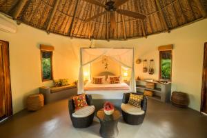 a bedroom with a bed and two chairs and a table at ONE Santuario Hotel y Reserva Natural in Palomino