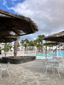 a patio with tables and chairs next to a pool at Confortable Apartment in Corralejo in Corralejo