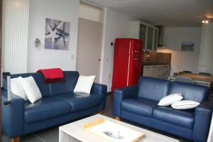a living room with two blue couches and a red refrigerator at Heggerank 3A in Nieuwvliet
