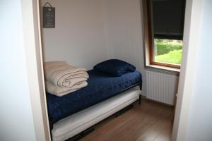 a small bed in a room with a window at Heggerank 3A in Nieuwvliet