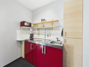 a kitchen with red cabinets and a sink at Boutique73 Sunrise in Ossiach