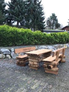 two wooden tables and benches sitting next to a stone wall at Suederhof-Diemelsee in Diemelsee