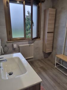 ein Badezimmer mit einem weißen Waschbecken und zwei Fenstern in der Unterkunft Affittacamere Ely in San Giórgio di Nogaro + 8 Fotos