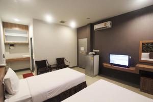 a hotel room with two beds and a flat screen tv at Seree Grand Resort in Hat Yai