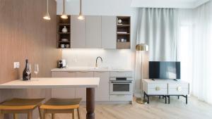 a kitchen with white cabinets and a sink and a tv at Sol Marina - Marina 165 in Wiślinka