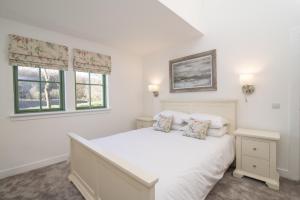 a white bedroom with a bed and two windows at The Steading InThePark in Stirling