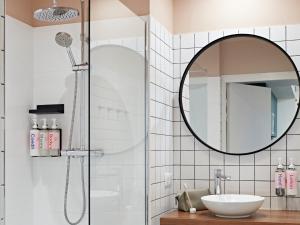 a bathroom with a shower and a sink and a mirror at YAYS Paris Issy by Numa in Issy-les-Moulineaux