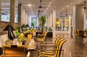 a restaurant with yellow chairs and tables in a lobby at The Blue Water - Geoffrey Bawa Heritage Resort Hotel in Wadduwa