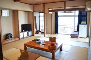 a living room with a table and a tv at Ryokan Fukuzen in Shibukawa