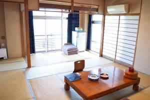 a living room with a table and a large window at Ryokan Fukuzen in Shibukawa