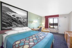 a hotel room with a bed with a large picture on the wall at Super 8 by Wyndham Barstow in Barstow