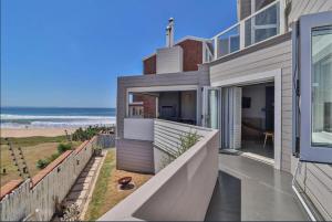 a house with a balcony with a view of the beach at Central, Beachfront Home in Jeffreys Bay