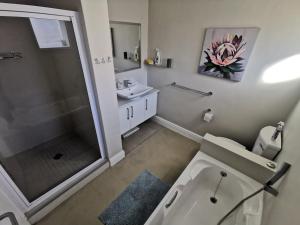 a bathroom with a shower and a toilet and a sink at Central, Beachfront Home in Jeffreys Bay